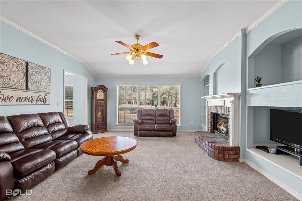 136 Scarborough Road Benton, LA 71006 - Photo 14 of 32 Spacious living area featuring a brick fireplace with a white mantel, built-in shelving, large windows, and a ceiling fan