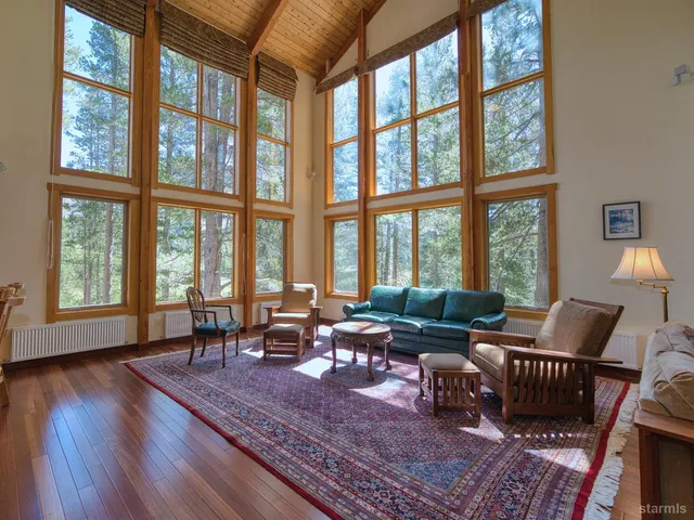 a living room with furniture large windows and wooden floor