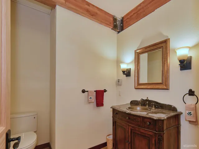 a bathroom with a granite countertop sink vanity mirror and toilet