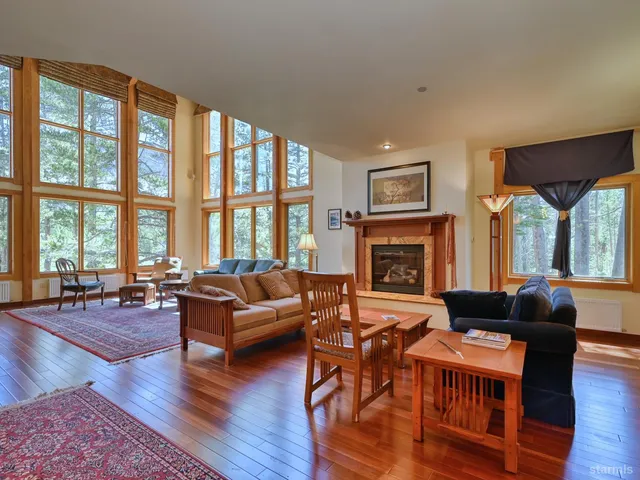 a living room with furniture large window and wooden floor