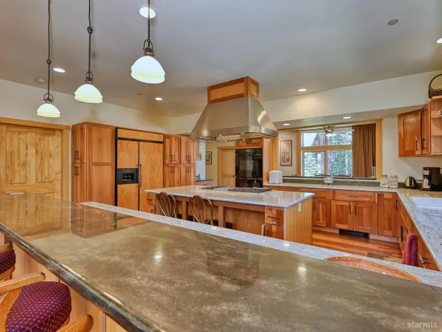 a large kitchen with stainless steel appliances a large counter top a stove and a sink
