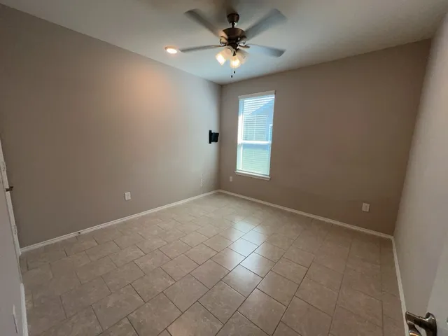 an empty room with a chandelier fan and windows