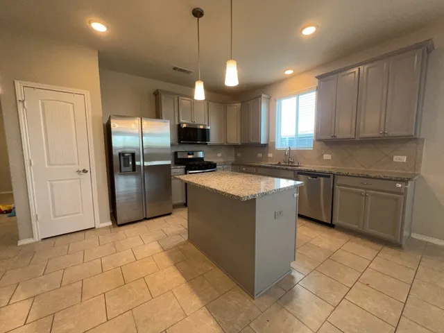 a kitchen with stainless steel appliances granite countertop a stove a sink and a refrigerator