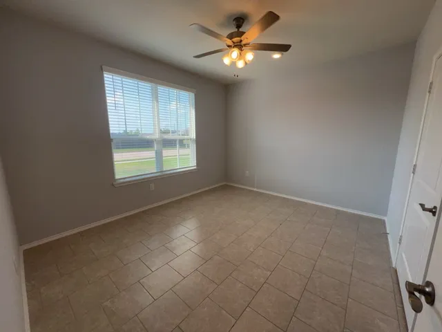an empty room with chandelier fan and windows