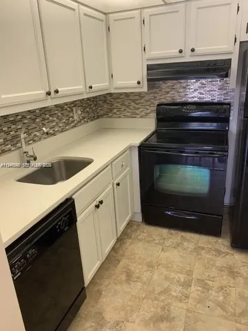 a kitchen with granite countertop white cabinets and stainless steel appliances