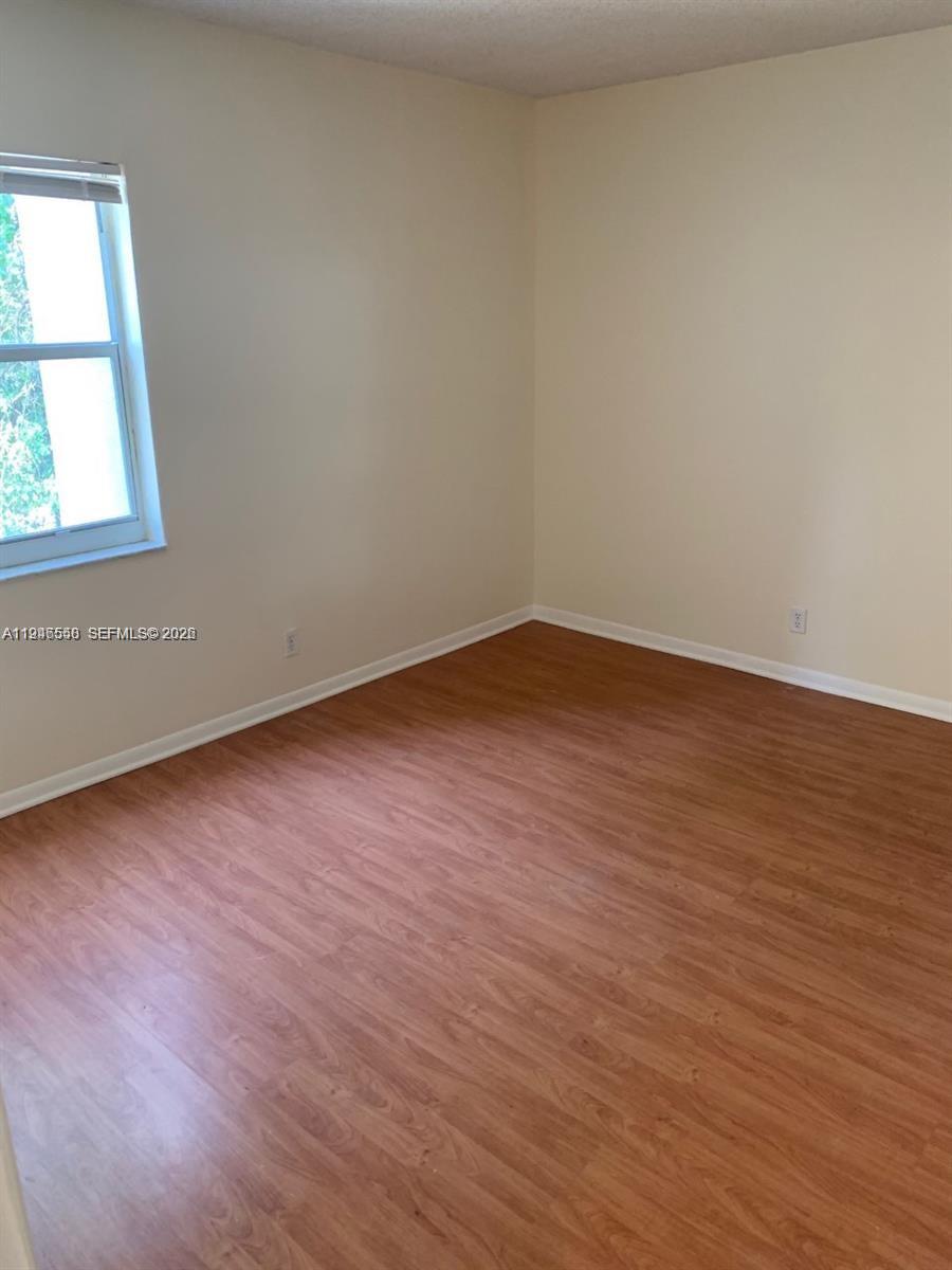 632 Northwest 13th Street, Unit 230 Boca Raton, FL 33486 - Photo 4 of 12 an empty room with wooden floor and windows