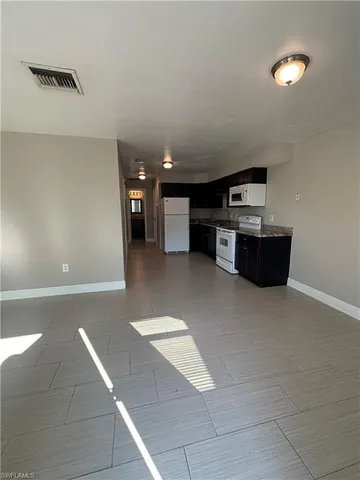 a living room with stainless steel appliances kitchen island granite countertop a rug and a stove