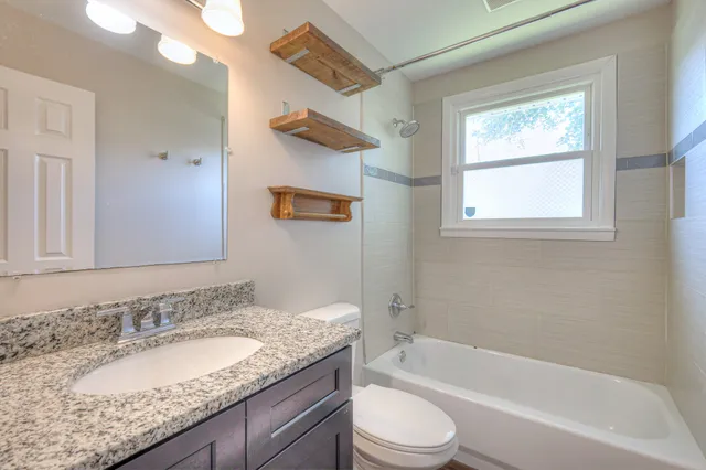 a bathroom with a granite countertop sink a toilet and bathtub