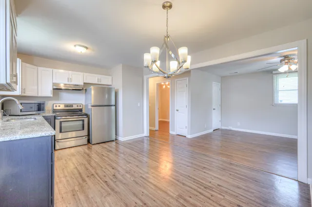 a kitchen with stainless steel appliances granite countertop a refrigerator a sink dishwasher a stove and white countertops with wooden floor