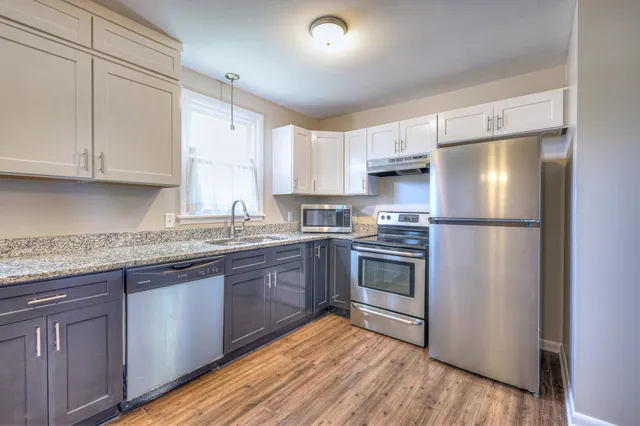 a kitchen with granite countertop a refrigerator stove and sink