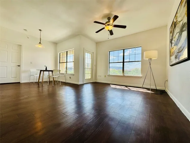 a dining room with wooden floor a chandelier a glass table and windows