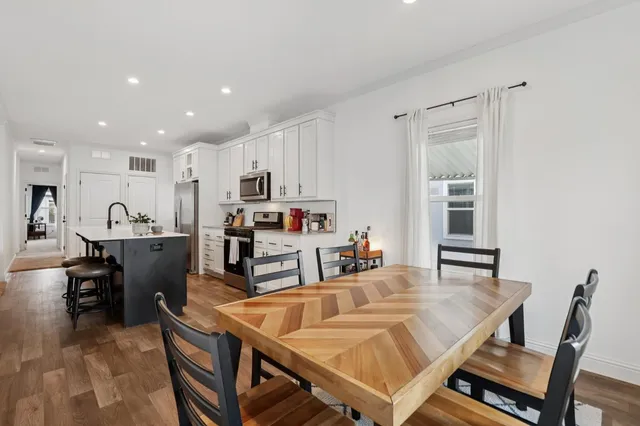 a living room with stainless steel appliances furniture a rug and a kitchen view
