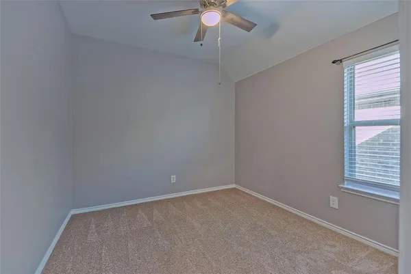 an empty room with a window and a fan