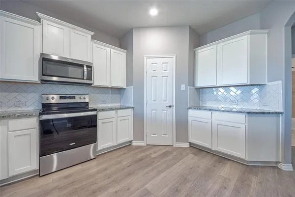 a kitchen with granite countertop white cabinets and stainless steel appliances
