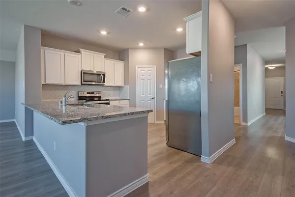 a kitchen with kitchen island granite countertop a refrigerator a sink a stove a microwave and cabinets