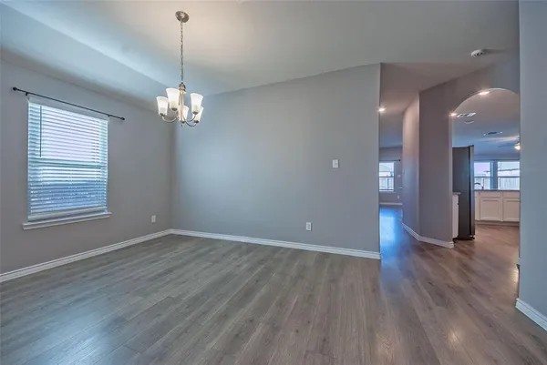 a view of an empty room with wooden floor and a chandelier