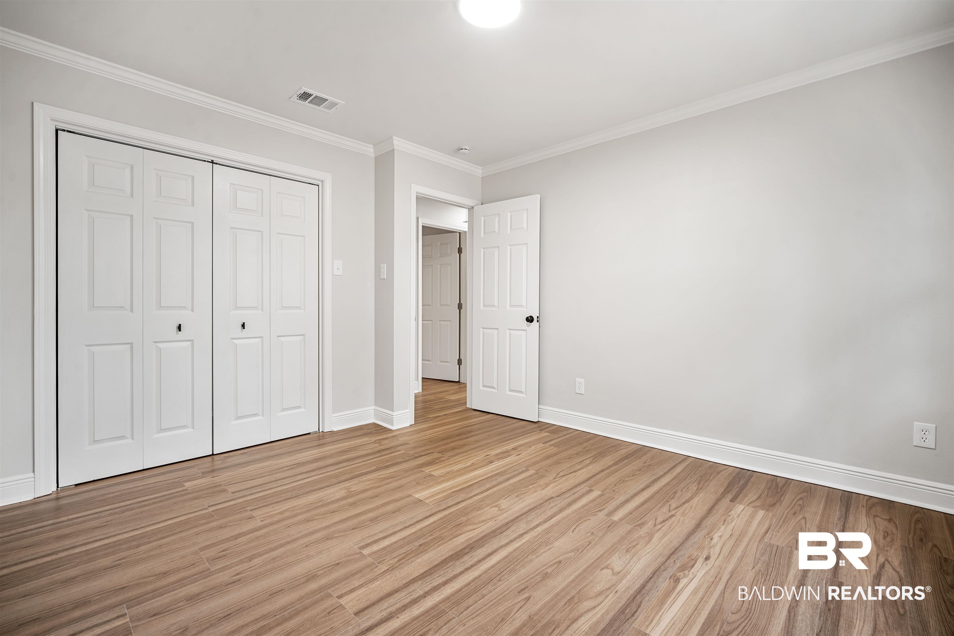 3050 Lacoste Road Mobile, AL 36618 - Photo 23 of 30 Unfurnished bedroom with ornamental molding, light wood-type flooring, and a closet