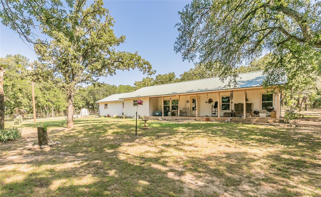 Front view of house featuring metal roof, a lawn, and covered porch