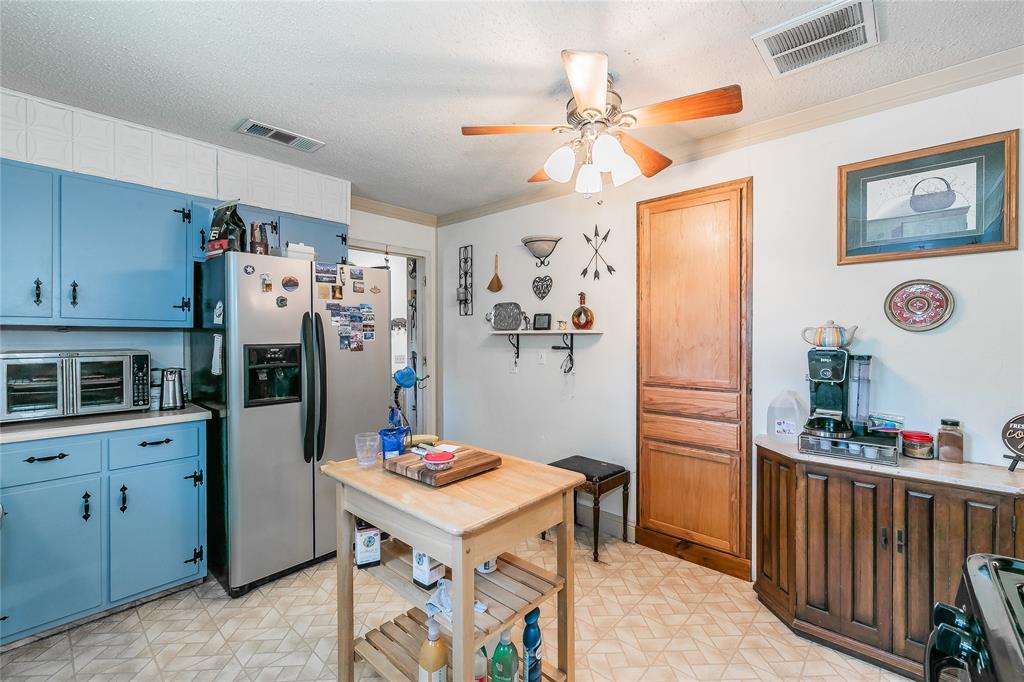 1055 Miller Road Azle, TX 76020 - Photo 11 of 40 Kitchen featuring stainless steel fridge with ice dispenser, a ceiling fan, light floors, light countertops, and blue cabinets