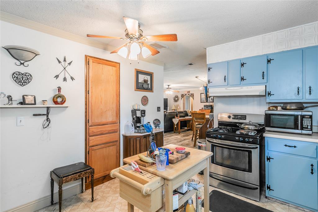 1055 Miller Road Azle, TX 76020 - Photo 12 of 40 Kitchen with blue cabinetry, stainless steel appliances, under cabinet range hood, ceiling fan, and a textured ceiling