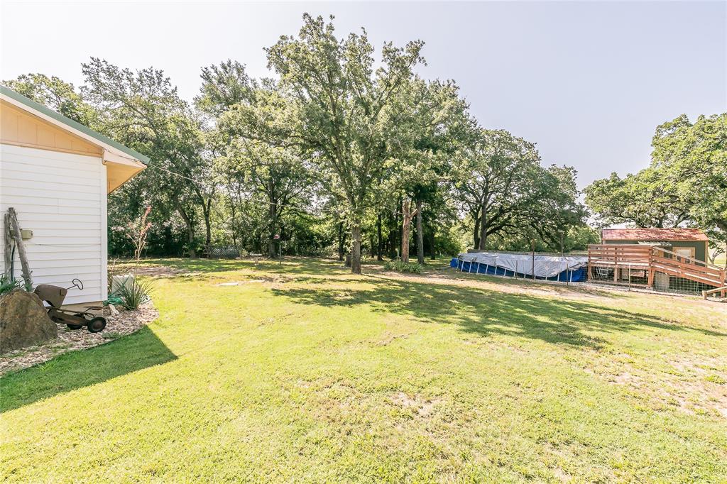 1055 Miller Road Azle, TX 76020 - Photo 28 of 40 View of green lawn with view of wooded area and above ground pool