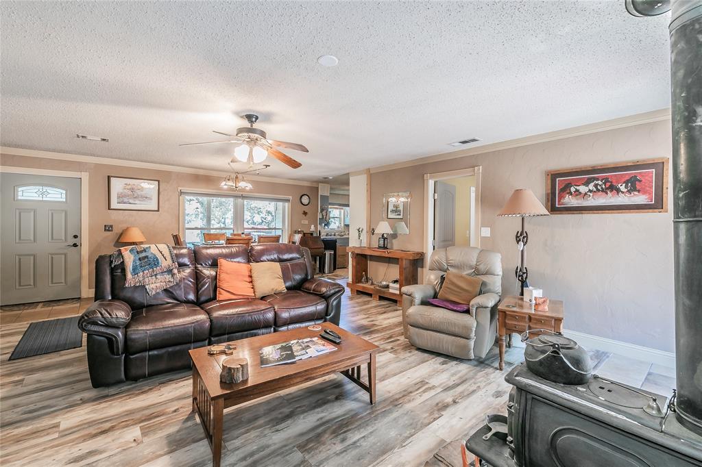 1055 Miller Road Azle, TX 76020 - Photo 7 of 40 Living room with a textured ceiling, light wood-style flooring, crown molding, ceiling fan, and baseboards