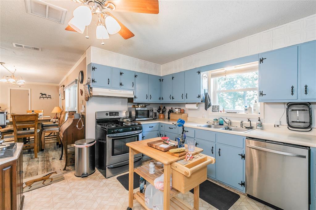 1055 Miller Road Azle, TX 76020 - Photo 10 of 40 Kitchen with appliances with stainless steel finishes, blue cabinets, a sink, under cabinet range hood, and a textured ceiling