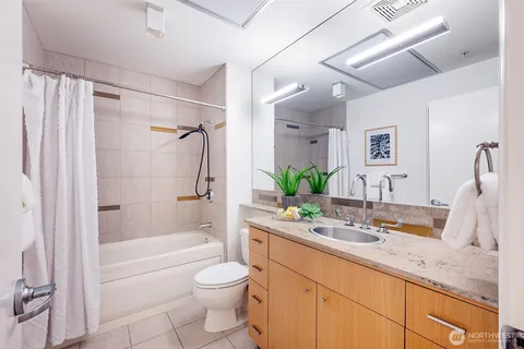 a bathroom with a granite countertop sink a mirror a bathtub and a shower