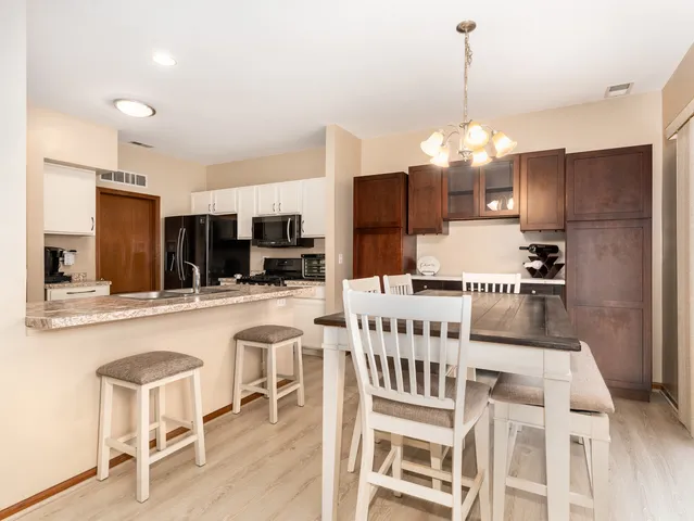 a kitchen with stainless steel appliances kitchen island granite countertop a dining table chairs and white cabinets