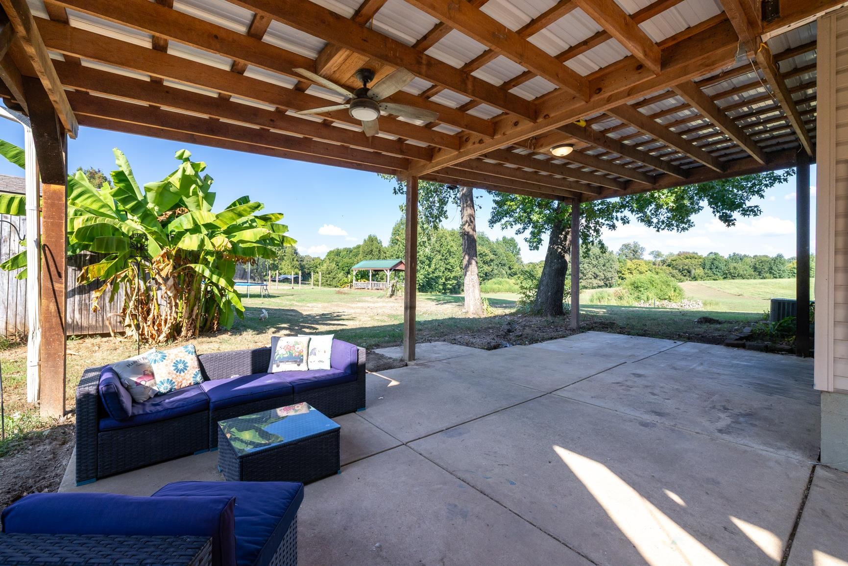 420 Sanford Road Covington, TN 38019 - Photo 24 of 27 Covered concrete patio with exposed wood beam ceiling, corrugated metal roof, and ceiling fan