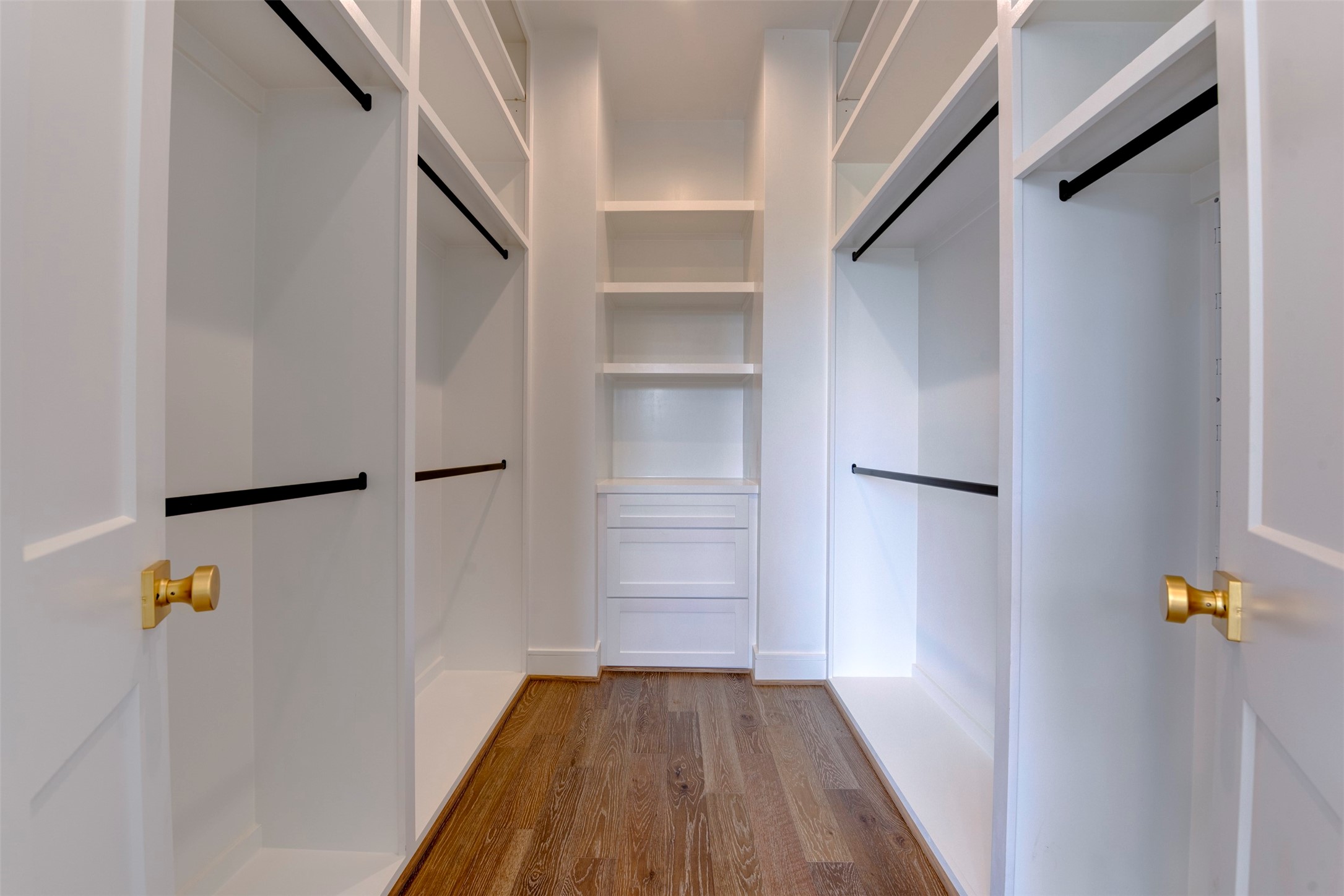 7120 Gary Street, Unit B Houston, TX 77055 - Photo 24 of 29 Spacious walk-in closet with ample shelving and hanging space, featuring polished wood floors and bright white cabinetry for a clean, modern look.