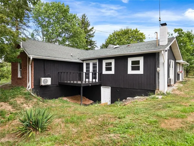 a house that is sitting in the grass with large trees