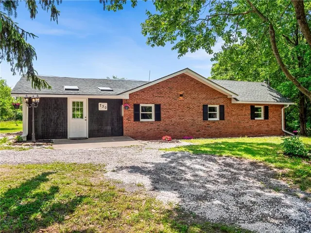a front view of a house with a garden and trees