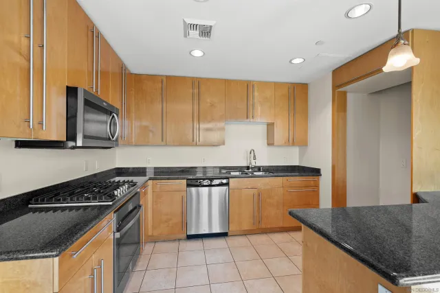 a kitchen with stainless steel appliances granite countertop wooden cabinets a stove top oven a sink and dishwasher