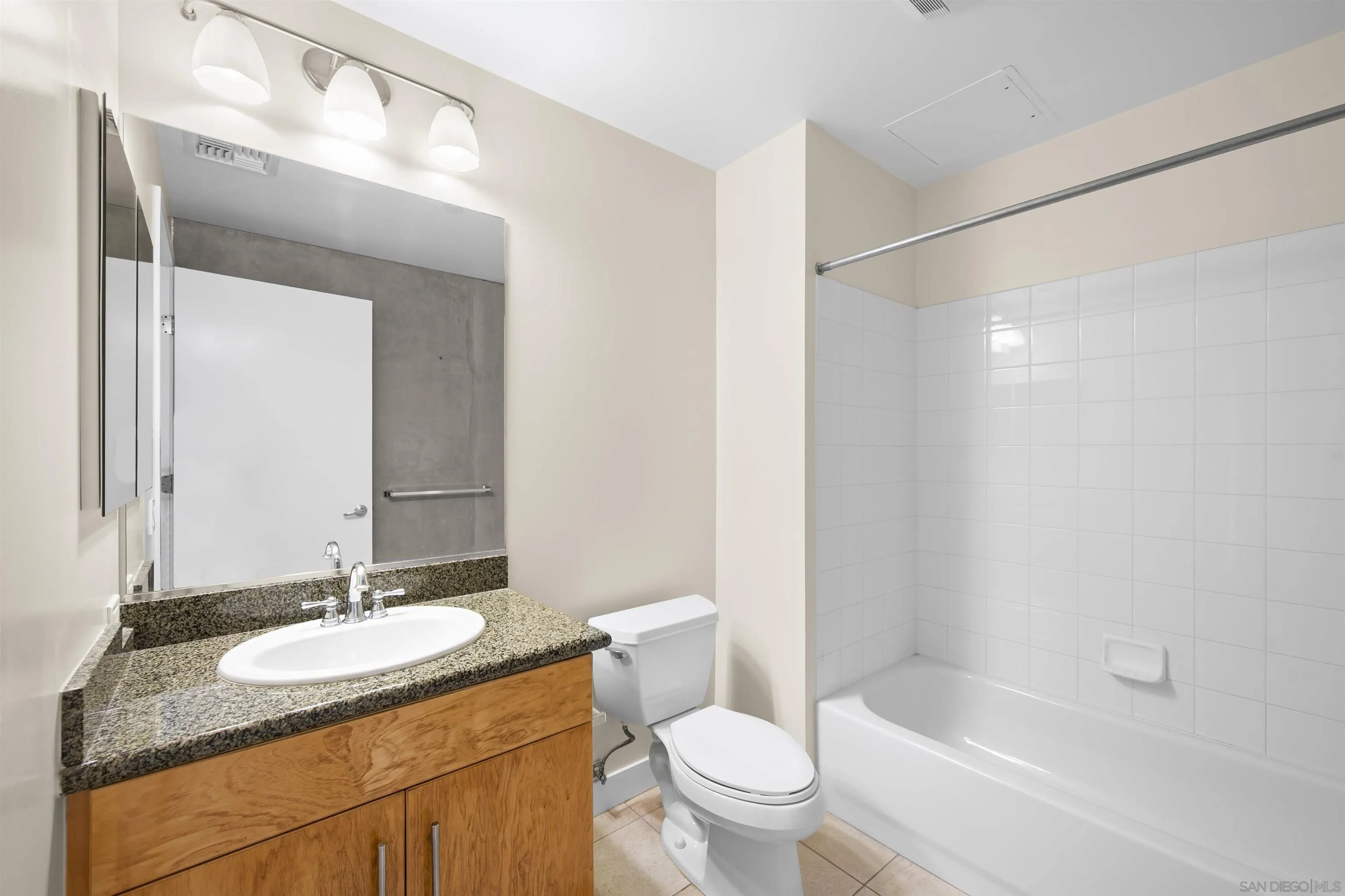 801 Ash Street, Unit 1701 San Diego, CA 92101 - Photo 29 of 44 a bathroom with a granite countertop sink a toilet a mirror and shower