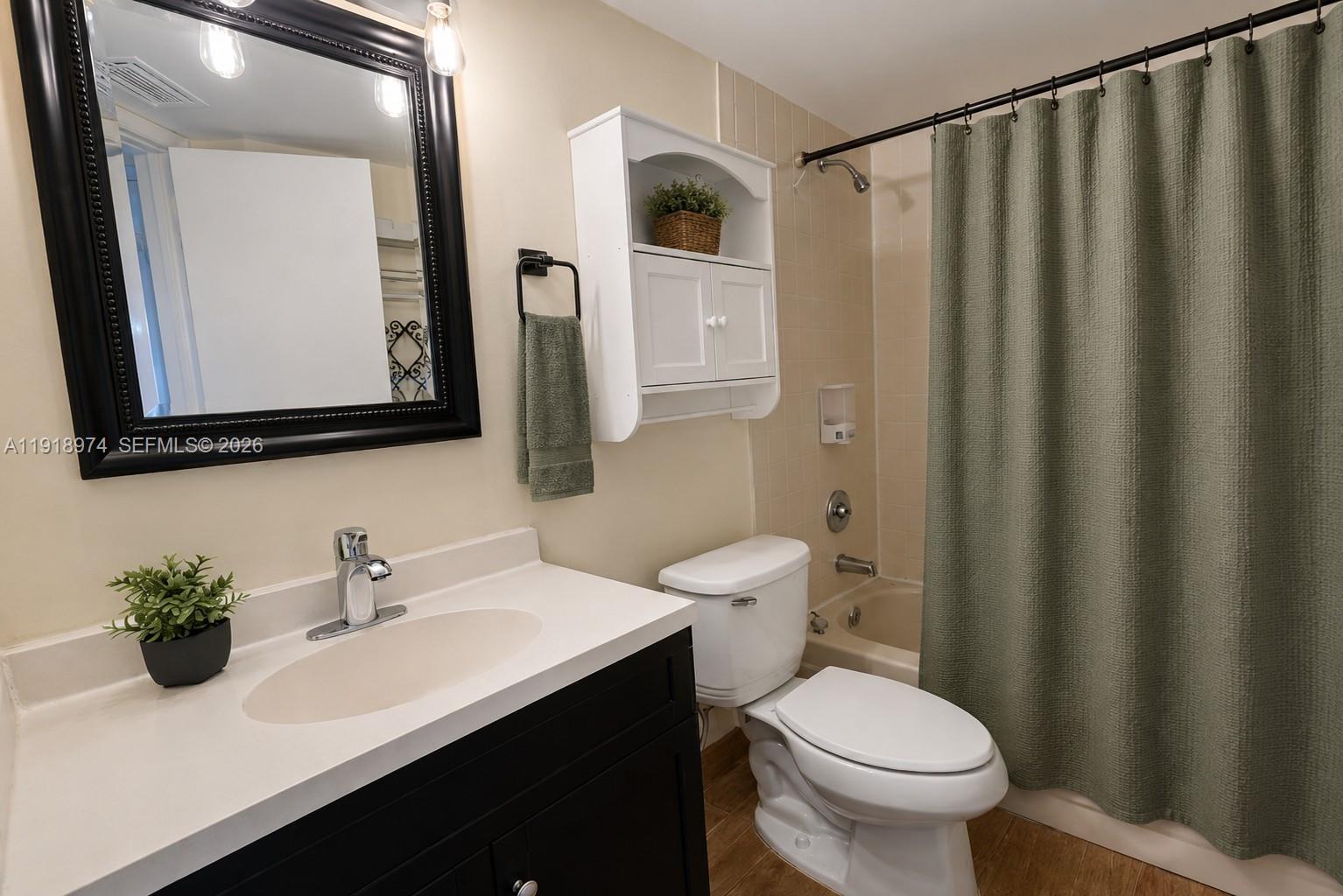 8801 Wiles Road, Unit 307 Coral Springs, FL 33067 - Photo 13 of 18 a bathroom with a sink a toilet a mirror and shower curtain