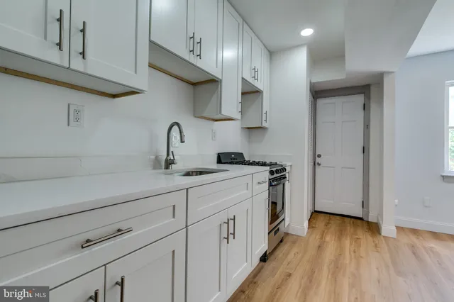 a kitchen with stainless steel appliances a sink dishwasher a stove and cabinets with wooden floor