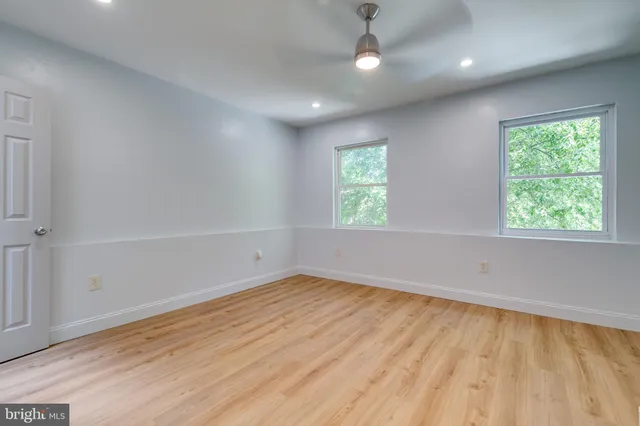 an empty room with wooden floor and windows