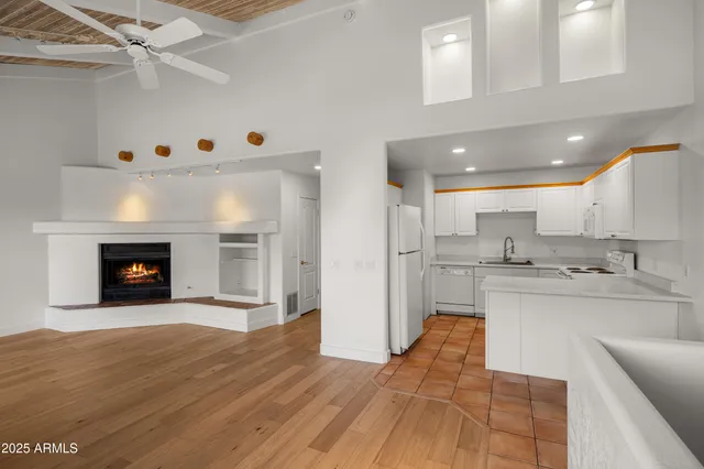 a kitchen with stainless steel appliances granite countertop a refrigerator a sink dishwasher and white cabinets with wooden floor