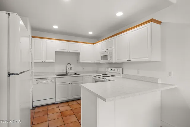 a kitchen with a sink a stove a refrigerator and white cabinets