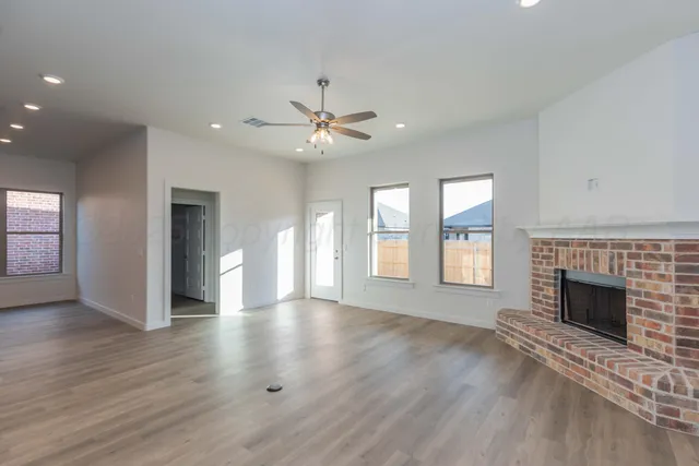 an empty room with windows fireplace and a kitchen view