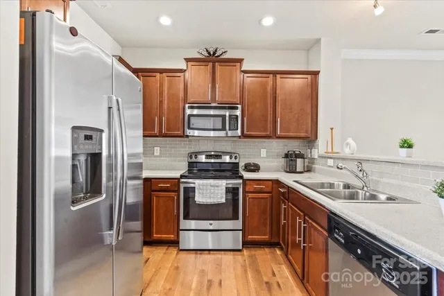 a kitchen with stainless steel appliances a sink cabinets and a wooden floor