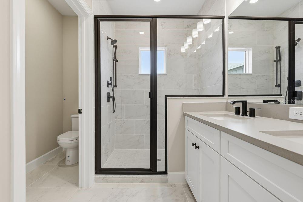 1624 Compass Pointe Court, Unit 203 Punta Gorda, FL 33950 - Photo 15 of 44 a bathroom with a granite countertop sink toilet and shower