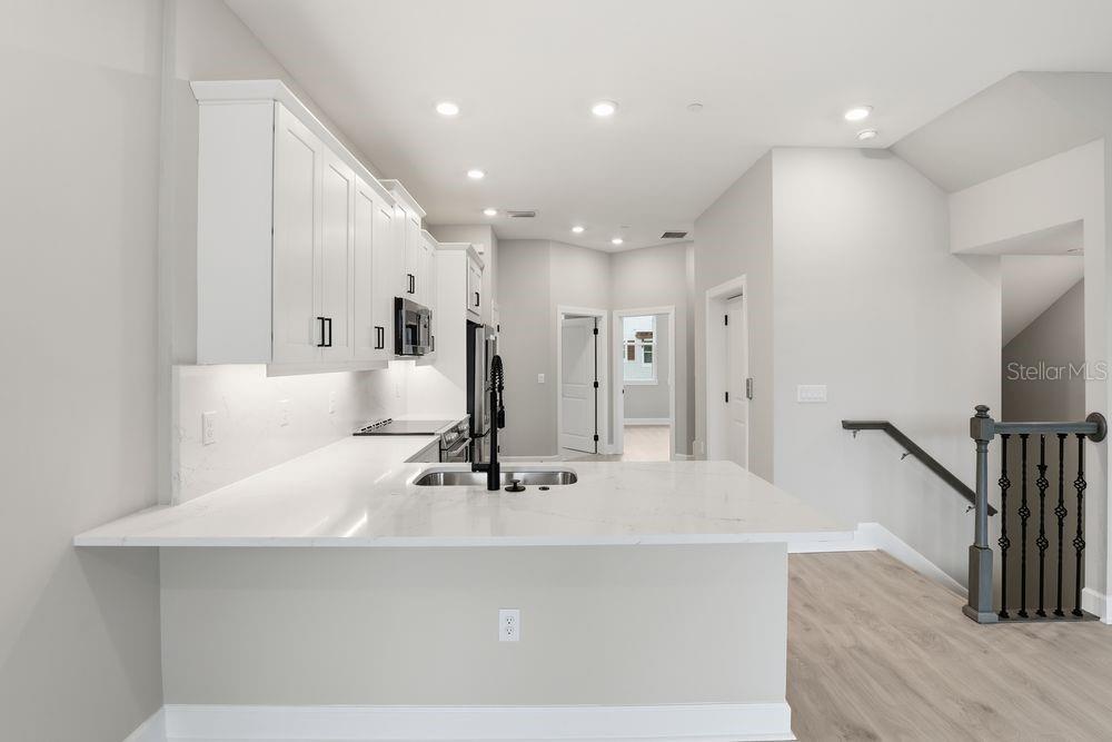 1624 Compass Pointe Court, Unit 203 Punta Gorda, FL 33950 - Photo 2 of 44 a large white kitchen with a large counter top and stainless steel appliances
