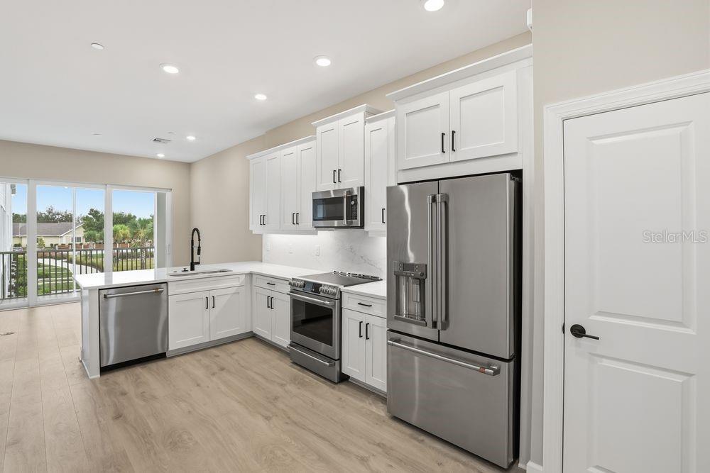 1624 Compass Pointe Court, Unit 203 Punta Gorda, FL 33950 - Photo 4 of 44 a kitchen with granite countertop stainless steel appliances a refrigerator a stove top oven and sink