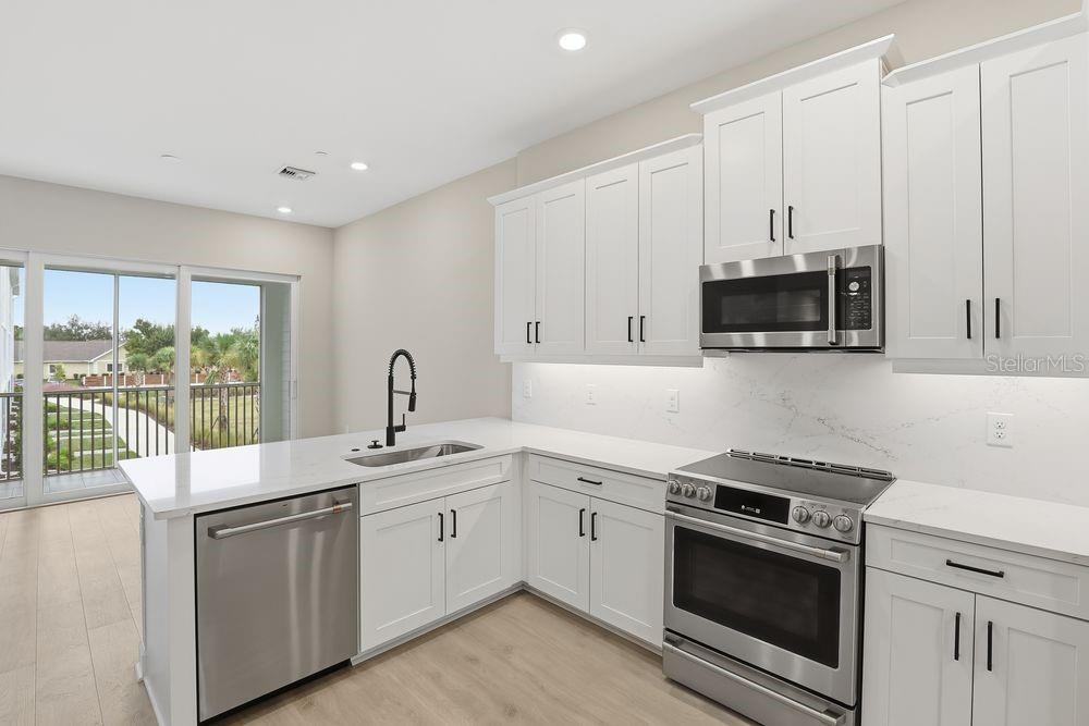 1624 Compass Pointe Court, Unit 203 Punta Gorda, FL 33950 - Photo 5 of 44 a kitchen with stainless steel appliances granite countertop a stove a sink and a microwave