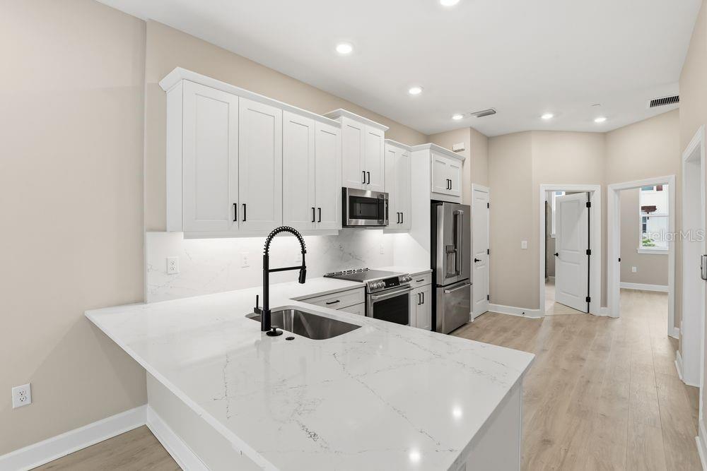1624 Compass Pointe Court, Unit 203 Punta Gorda, FL 33950 - Photo 6 of 44 a kitchen with stainless steel appliances a refrigerator sink and wooden cabinets