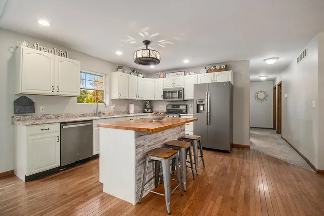 a kitchen with a refrigerator a sink dishwasher a stove and white cabinets with wooden floor