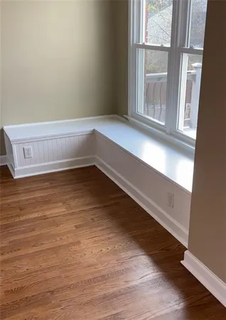 an empty room with wooden floor fan and window