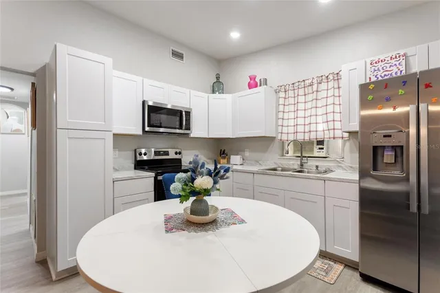 a kitchen with stainless steel appliances granite countertop a sink a microwave a refrigerator and white cabinets